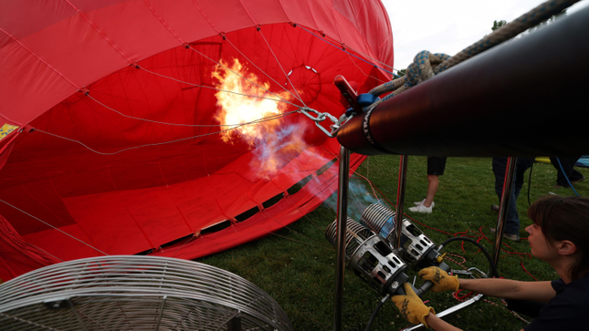 The red hot air balloon is inflated by the flame of the burner.